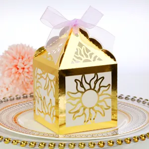 Close-up of laser-cut gold mirror paper favor box with pink ribbon and sunburst pattern