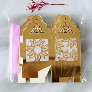 Flat lay of laser-cut gold sunburst paper favor boxes with pink silk ribbon