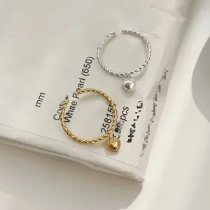 Macro view of twisted S925 sterling silver rings with hanging heart charm detail