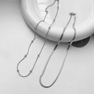 Detailed view of silver double-layered snake chain and beaded necklace with lobster clasp