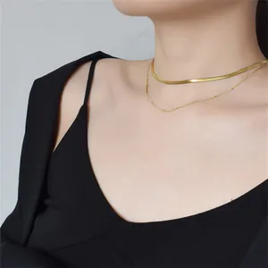 Chic double layer gold snake chain necklace set worn by a fashion model on a dark top
