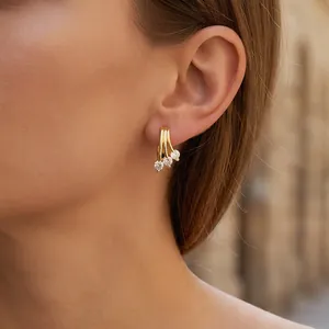 Close-up of golden line earrings with micro-inlaid zircon clusters on model's ear