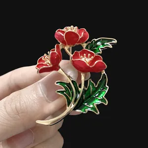 Detalle de un broche de amapola roja esmaltada con acabados en tono dorado