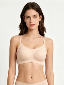 Front view of beige seamless bra with slim straps and smooth fabric on light gray background