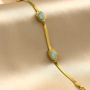 Dettaglio della collana a catena serpente dorata con pietre turchesi su raso