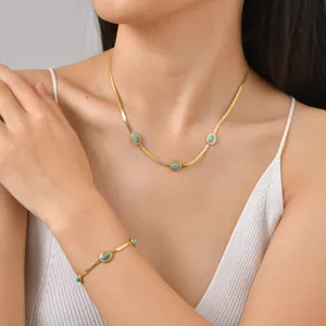 Dettaglio di set collana e bracciale a serpente dorati con pietre turchesi su modella