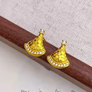 Macro shot of fan-shaped gold earrings with scale texture and sparkling zircon accents