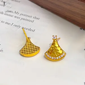 Detailed macro view of fan-shaped gold stud earrings with textured finish and zircon stones