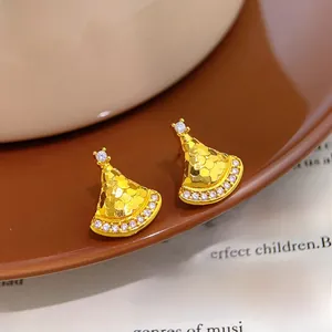 Detail of fan-shaped gold earrings with scale texture and sparkling zircon inlay