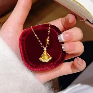 Elegant gold-plated fan-shaped pendant necklace with crystal accents on a velvet cushion