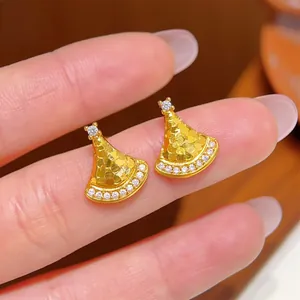 Macro shot of gold fan-shaped stud earrings with honeycomb texture and tiny diamonds