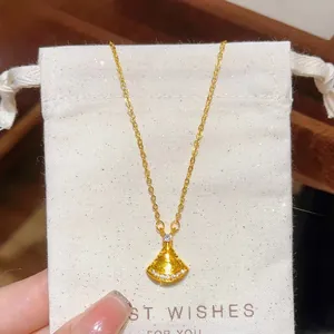 Detail of a fan-shaped gold necklace with sparkling crystals and a white drawstring pouch