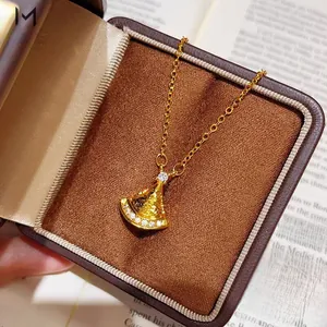 Macro detail of a fan-shaped gold pendant necklace with white diamonds on a velvet jewelry box