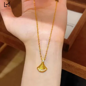 Close-up of golden fan-shaped necklace pendant with sparkling white pavé diamonds