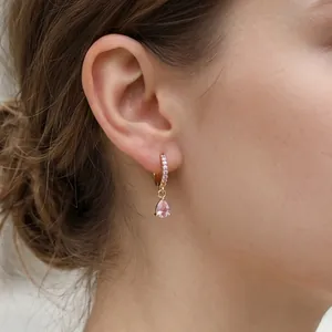 Dettaglio orecchini a goccia dorati con zircone rosa a pera e pavé di cristalli