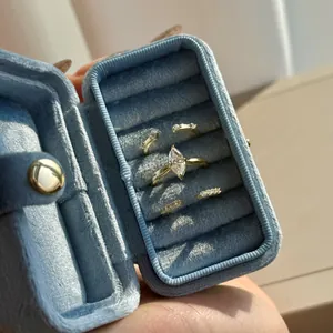 Golden stackable rings with marquise-cut white stones in a light blue velvet jewelry box