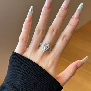 Pear cut halo ring set with cubic zirconia on female hand in warm lighting