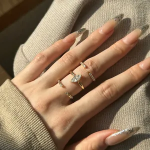 Close-up of gold marquise cut zircon rings set worn against a beige knit background