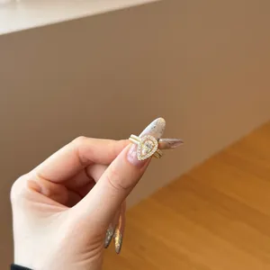 Detail of s925 silver pear cut white zircon halo ring and stacked gold band