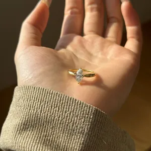 Macro shot of marquise-cut zircon on gold plated ring band shown on a palm