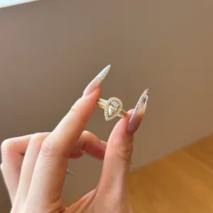 Close-up of golden pear-shaped double ring set with micro-pave crystals on hand