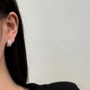 Detalle de pendientes de aro en plata s925 con pavé de circonitas en una oreja femenina