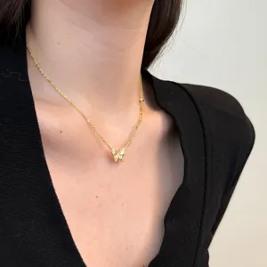 Detail van een gouden vlinderketting met zirkoon op een asymmetrische moderne schakelketting