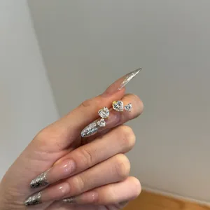 Close-up of heart-shaped zircon earrings in gold claw setting held by hand