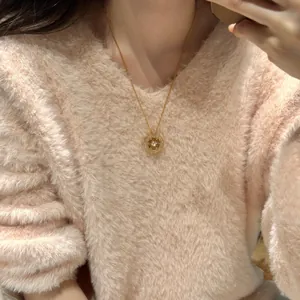 Détail du pendentif boussole en argent s925 avec diamants sur pull rose