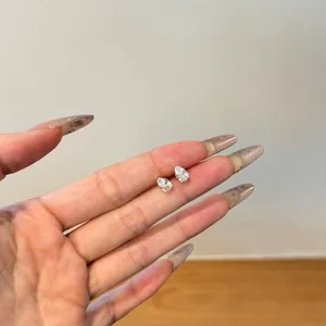 Detailed view of pear-cut crystal stud earrings held by hand to show size and sparkle