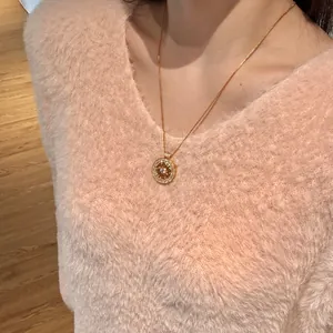 Collier boussole en argent S925 doré porté sur un pull en peluche rose doux