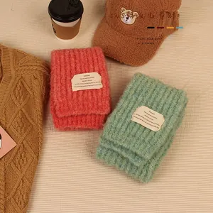 Close-up of pink and green knitted children's scarves with soft texture and white label
