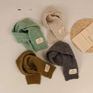 Detailed knit texture of four colored children's scarves with stitched labels