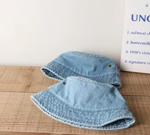 Détail du bob en denim délavé bleu clair montrant les œillets métalliques et le coton