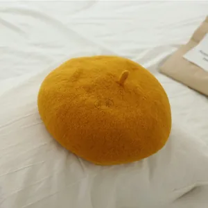 Detailed texture of a bright yellow wool beret hat for girls on soft white fabric