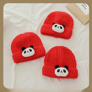 Détail de bonnets rouges en grosse maille pour enfants avec écussons panda pour l'hiver