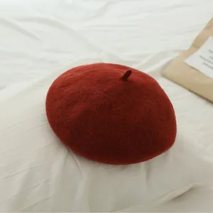 Close-up of deep red wool felt beret for girls with top stem detail on white cloth