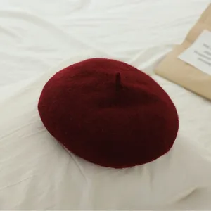 Detailed texture of burgundy wool beret for girls on soft white fabric background