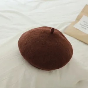 Detail shot of a warm brown wool beret featuring soft textured fabric and a top stem