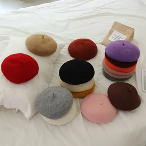 Flat lay of soft wool beret hats for girls in multiple colors on white bedding