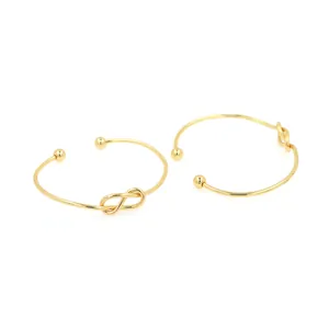 Brazaletes abiertos bañados en oro de 18K con nudo minimalista y extremos de esfera
