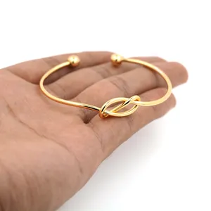 Brazalete abierto bañado en oro de 18K con diseño de nudo y puntas de bola dobles