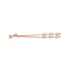 Détail du bracelet en or rose avec fermoir coulissant et pierres précieuses vertes