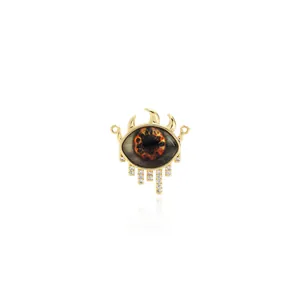 Macro shot of 18K gold plated evil eye pendant with brown iris and sparkling tassels
