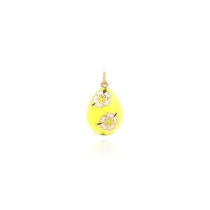 Detailed view of yellow enamel egg pendant with white flower patterns and gold trim
