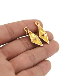 Detailopname van 18K vergulde geometrische ruitvormige hangers in de hand gehouden