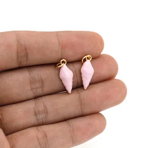 Detailed close-up of pink shell pendants with gold plated rings held by hand