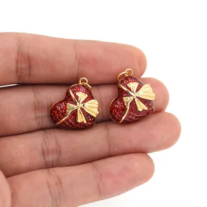 Dettaglio di ciondoli a cuore placcati oro 18K con fiocco tenuti in mano