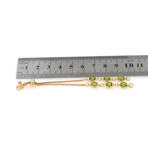 Detailed view of adjustable 18K gold-plated bracelet with green stones and scale measurement