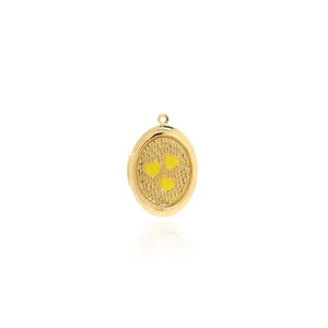 Macro view of a 18K gold-plated oval locket with yellow heart patterns and embossed details